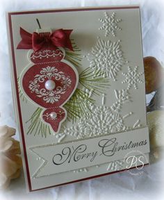 a christmas card with a red ornament hanging from it's side and snowflakes on the bottom