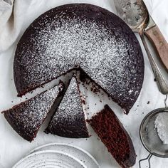 a chocolate cake with powdered sugar on top and one slice cut from the cake