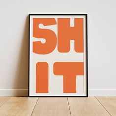 an orange and white poster with the words shut it in bold font on a wood floor