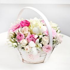 a white basket filled with pink and white flowers