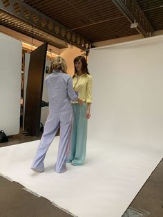 two women standing in front of a white backdrop