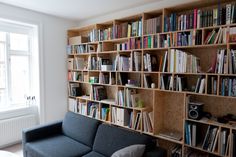 a couch sitting in front of a book shelf filled with books