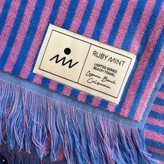 a purple and blue striped scarf with fringes on it's end, next to a tag that says ruby mint limited fabrics