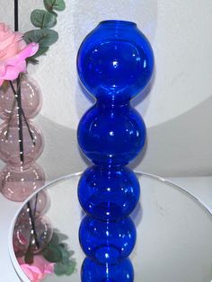 three glass vases sitting on top of a white table next to a pink flower