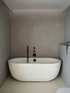 a large white bath tub sitting next to a toilet in a bathroom under a window