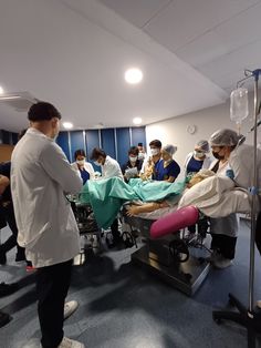 a group of people in scrubs standing around a hospital bed with medical equipment on it