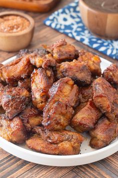 a plate full of chicken wings on a table with other food items in the background