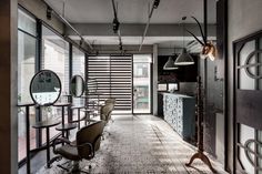 an empty salon with chairs and mirrors on the walls, along with lights hanging from the ceiling