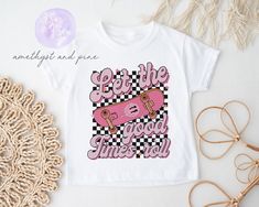 "Let your little one show off their skater style with our pink skateboard t-shirt for girls! Featuring a graphic of a pink skateboard on a black and white checkered background, this tee is sure to stand out. The pink text reading \"Let the good times roll\" gives the shirt a fun, carefree vibe. This girls' t-shirt is comfortable and durable, making it perfect for active kids. Whether they're hitting the skate park or just playing with friends, this tee will keep them looking and feeling great. Available in toddler and kids' sizes, this pink skateboard t-shirt is the perfect addition to any young skater's wardrobe. Pair it with jeans, shorts, or a denim skirt for an effortlessly cool look. And with its grunge-inspired style and retro feel, this shirt is sure to appeal to parents and kids al Unisex Pink Playful T-shirt, Pink Skateboard, Girl Skater, Checkered Background, Background Baby, Skater Shirts, Skate Girl, Skateboard Tshirt, Let The Good Times Roll