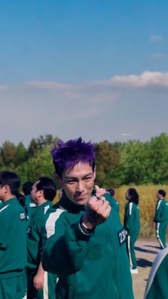 a group of young men standing next to each other wearing green jackets and purple hair