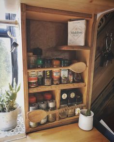 a wooden shelf filled with spices next to a potted succulent and a window