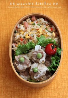 a wooden bowl filled with rice, meat and veggies on top of a table