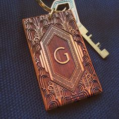 a wooden keychain with the letter g on it and an ornate design is shown