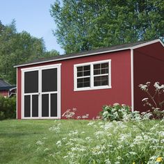 a red shed sitting on top of a lush green field