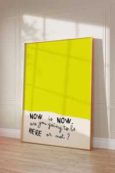 there is a yellow poster on the floor in front of a white wall with black writing that says now is now, are you going to let here on most?