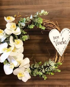 a heart shaped wreath with white flowers and greenery