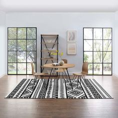 a modern dining room with wood floors and white walls, along with an area rug that has geometric designs on it