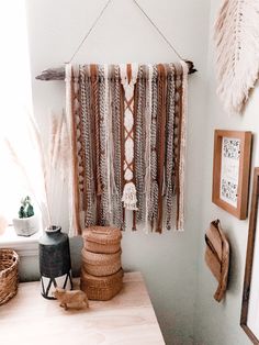 a wall hanging made out of yarn and feathers on a wooden table in a room