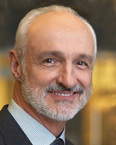 a man in a suit and tie smiling at the camera