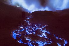 the lava is glowing blue as it flows into the ocean at night with clouds in the background