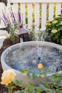 a water fountain surrounded by plants and flowers