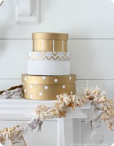 a three tiered cake with gold and white decorations on top, sitting on a mantle