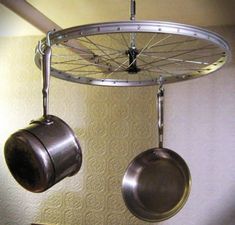 two pots and pans hanging from a ceiling fixture with wheels attached to the ceiling