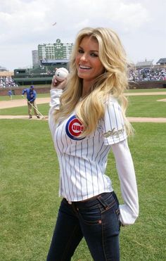 a beautiful young blond woman standing on top of a baseball field