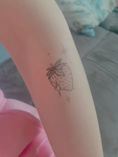 a woman's arm with a small tattoo of a strawberry on the left side