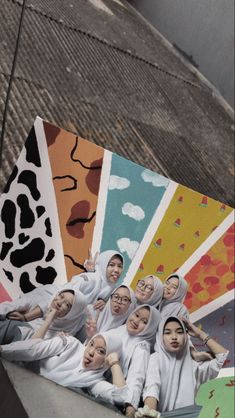 a group of young women standing next to each other in front of a mural on the side of a building