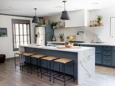 an image of a kitchen with marble counter tops and stools on the island in front of it