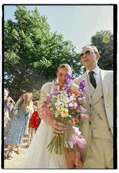 a man in a suit and tie standing next to a woman holding a bouquet of flowers