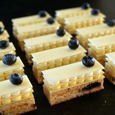 small desserts with blueberries are arranged on a black table top, ready to be eaten