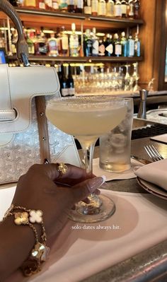 a person is holding a glass in front of a bar