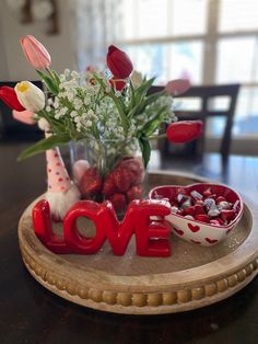 a wooden tray topped with flowers and love letters