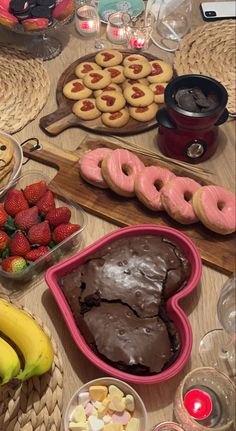 a table topped with lots of desserts and cookies next to bowls filled with fruit