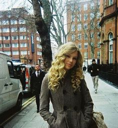 a woman standing on the sidewalk with her hands in her pockets