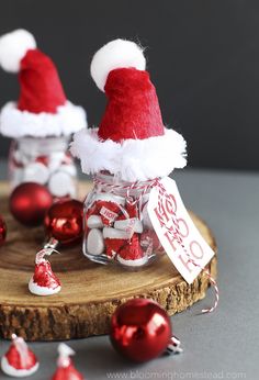 two santa hats sitting on top of a glass jar filled with candy