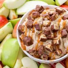 a bowl filled with ice cream surrounded by apples and caramel chunks on top of it