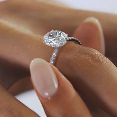 a woman's hand holding an engagement ring with a diamond on it and the band around her finger