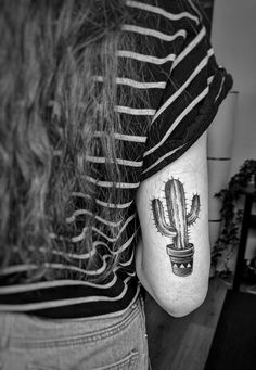 a woman with a small cactus tattoo on her left shoulder