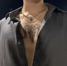 a man with tattoos on his chest wearing a black shirt and silver chain around his neck