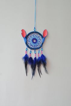 a blue and red dream catcher hanging on a wall next to a black cat toy