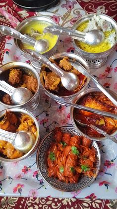 a table topped with bowls filled with different types of food and spoons next to each other