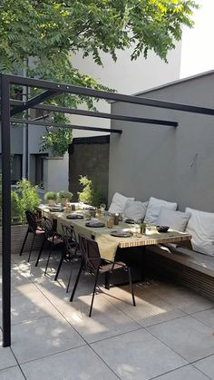 an outdoor dining area with tables and chairs on the patio, surrounded by greenery