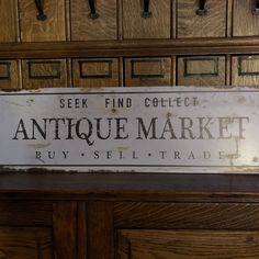 an antique market sign is hanging on the wall in front of some filing cabinets and drawers