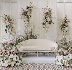 a white couch surrounded by flowers and greenery