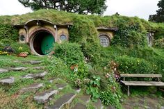 a green hobbot house surrounded by flowers and greenery