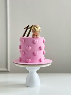 there is a pink cake with hearts and a monkey on top that has an arrow sticking out of it