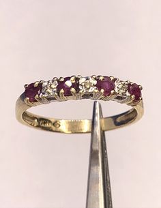 * Designer 10K Yellow Gold Round Ruby Diamond Stackable Anniversary Band Ring * Ring size: 6 * Band width: 2.2 mm * Top of ring measures: 5/8" x 1/8" * Height: 1/8" * 4 Round Rubies measure approximately 2.5 mm each  * 3 Round Diamond Chips measure approximately 0.7 mm each * Weight: 1.5 tgw * Marked: Makers Mark * 14K  * Condition: As pictured. * G4122    Exported By ExportYourStore :) Classic Stackable Ruby Rings, Classic Ruby Stackable Rings For Anniversary, Classic Half Eternity Ruby Ring, Classic Diamond Ruby Stackable Ring, Classic Ruby Half Eternity Ring For Anniversary, Classic Half Eternity Ruby Ring For Anniversary, Classic Stackable Ruby Ring For Anniversary, Stamped 14k Gold Bands For Anniversary, Stamped 14k Band Rings For Anniversary